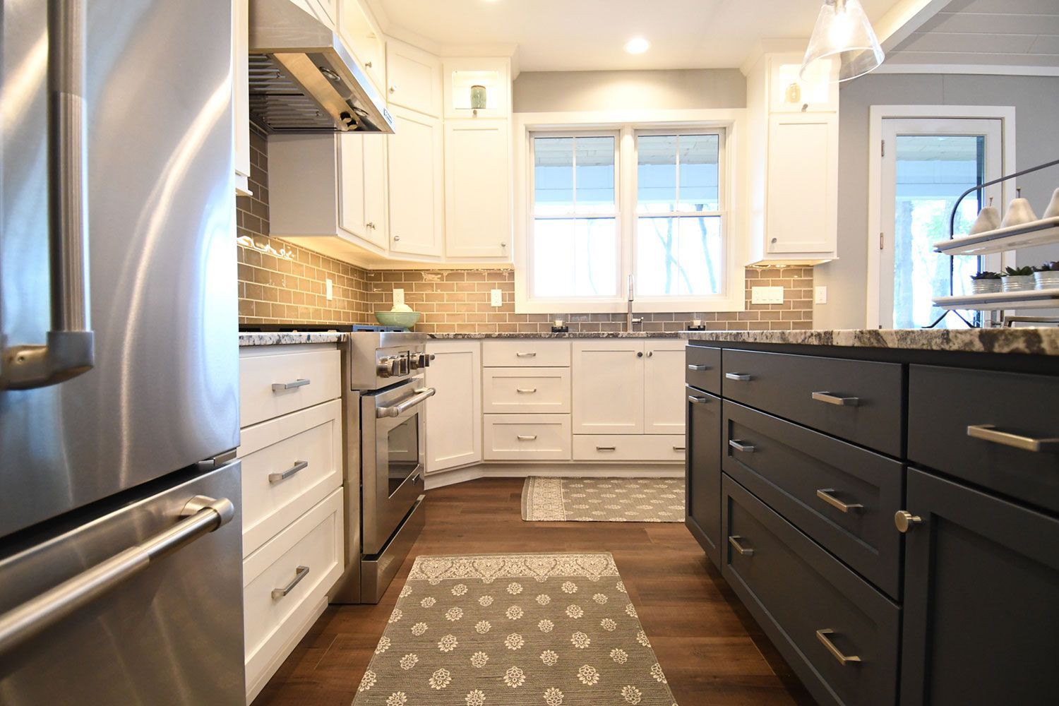 Modern kitchen with white cabinets, stainless steel appliances, and a dark gray island.
