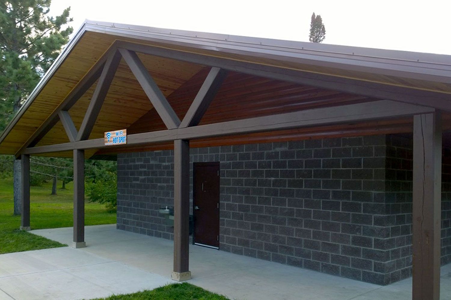 Covered brick building with wooden supports and a brown roof.