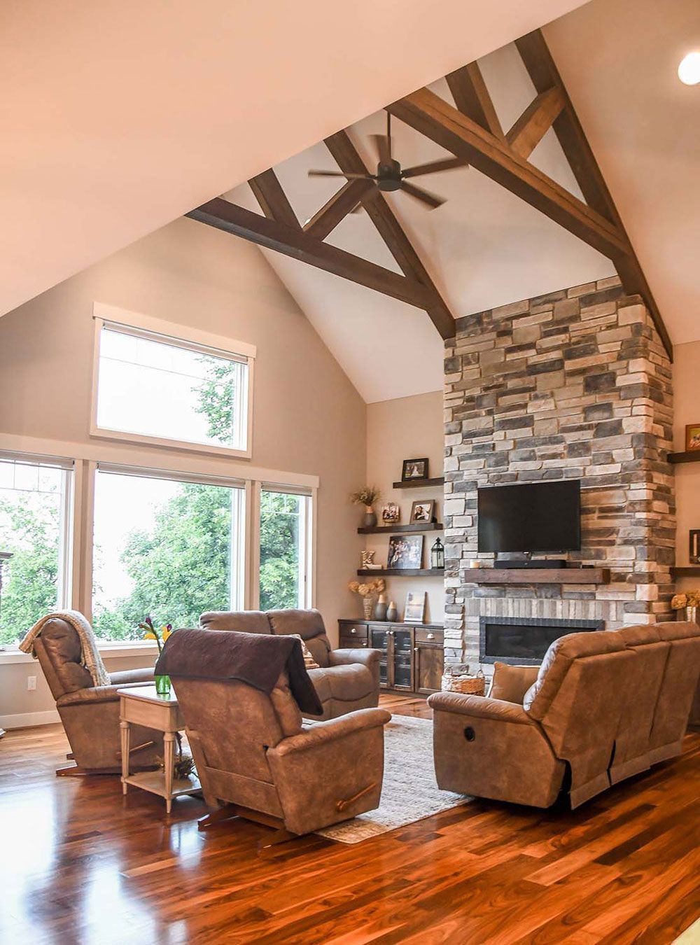 Living room with stone fireplace, recliner chairs, and high wood beam ceiling.
