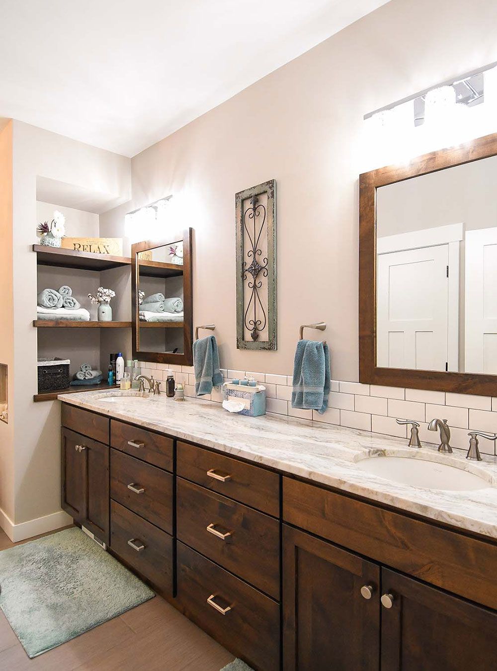 Bathroom with double vanity and brown cabinetry. White countertop, beige walls, and recessed shelving.