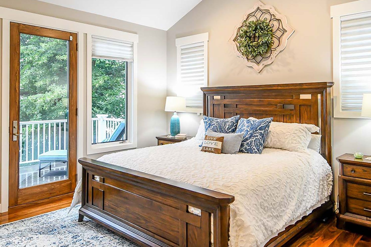 Bedroom with wooden bed, door to balcony, neutral tones, and green outdoor view.