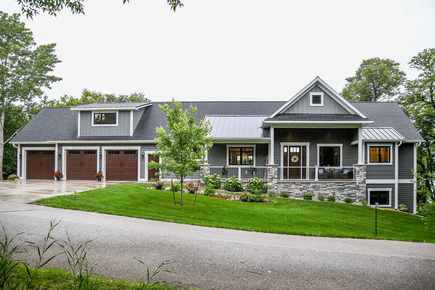 Gray house with brown garage doors, stone accents, and green lawn.