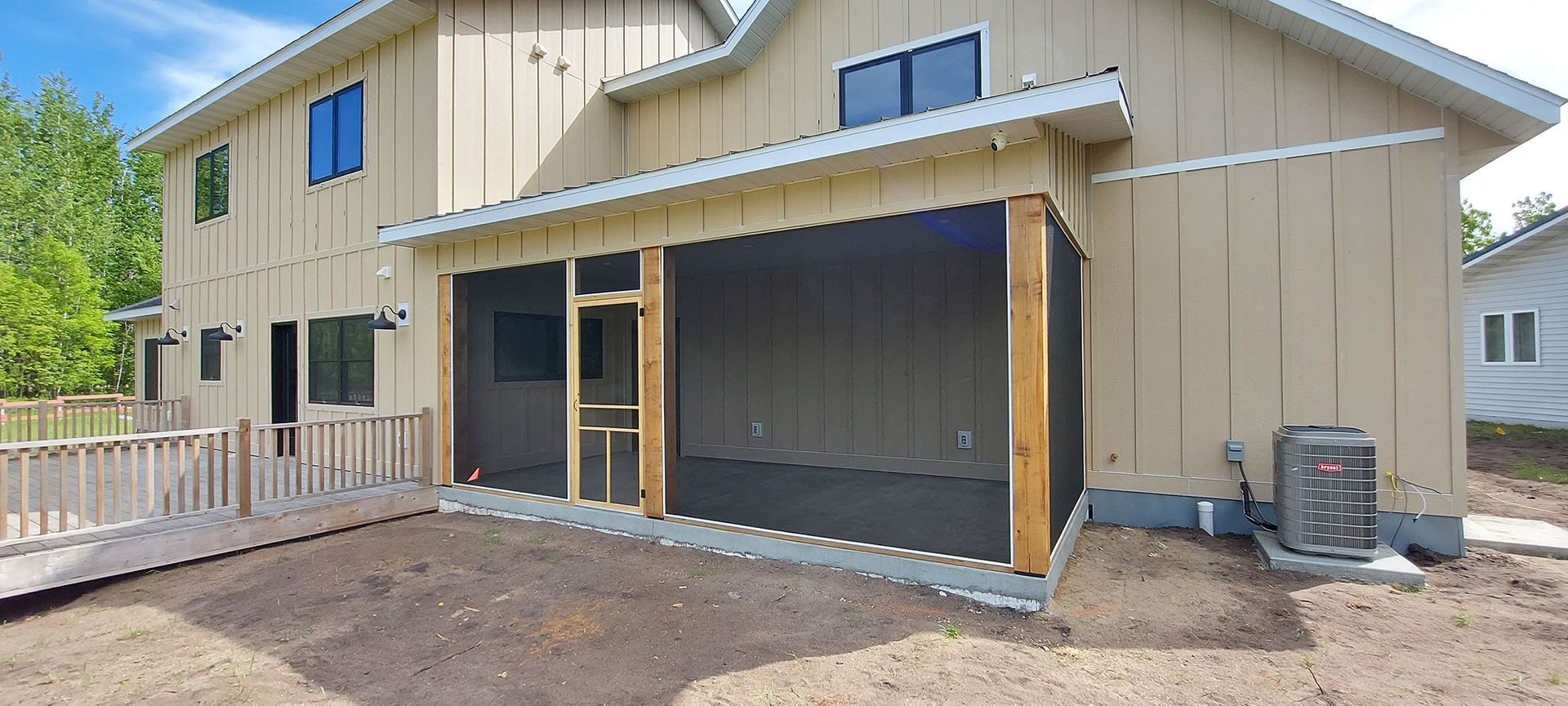 Backyard with a screened-in porch, ramp, and air conditioning unit. Beige siding and a newly-laid dirt area.