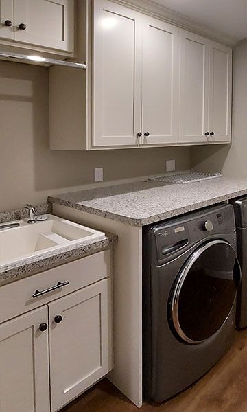 Laundry room with white cabinets, gray countertop, and washing machine.