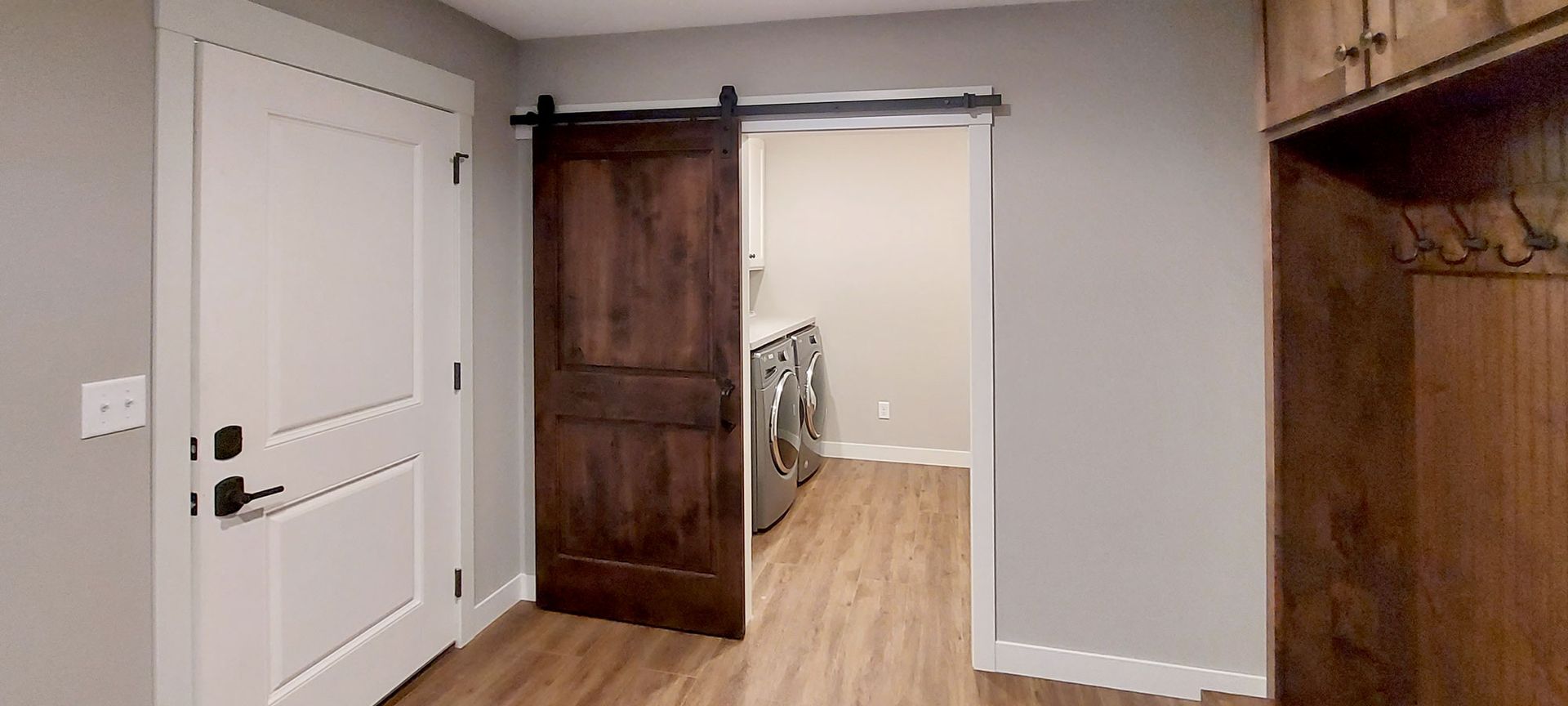 Interior room with a white door on the left, barn door in the middle, and wooden storage on the right.