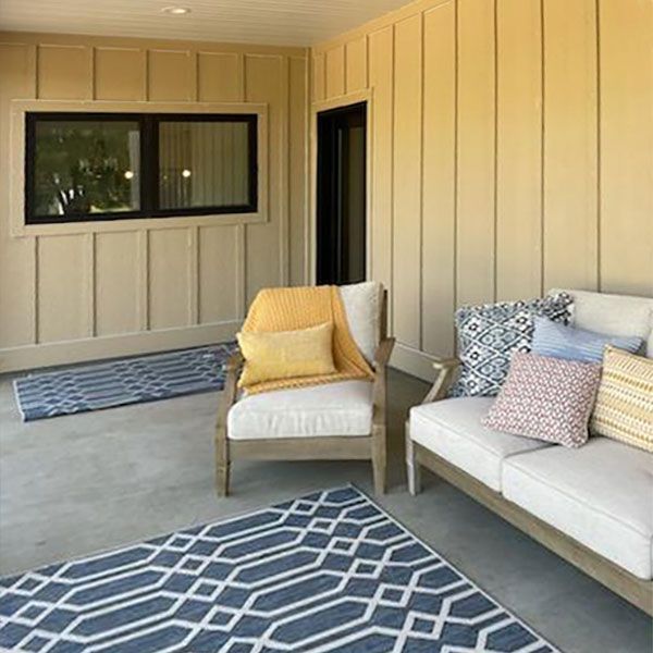 Patio with a blue rug, cream-colored sofa, and tan walls. Includes a chair and pillows.