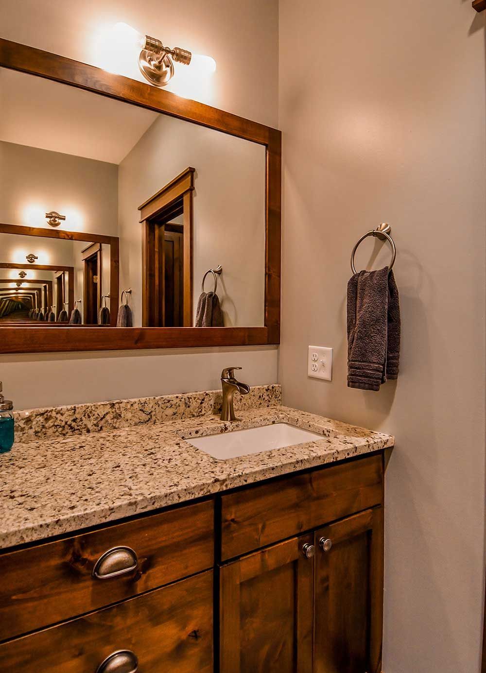 Bathroom with brown wooden vanity, granite countertop, mirror, and towel.