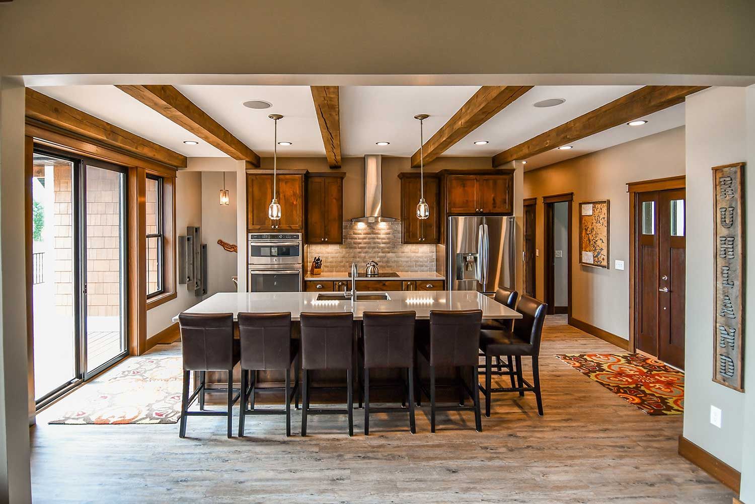Modern kitchen with large island, wood beams, and stainless steel appliances.
