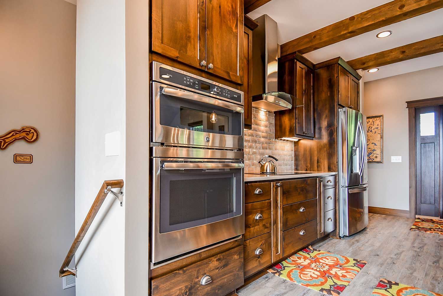 Kitchen with stainless steel appliances, dark wood cabinets, and colorful rug.