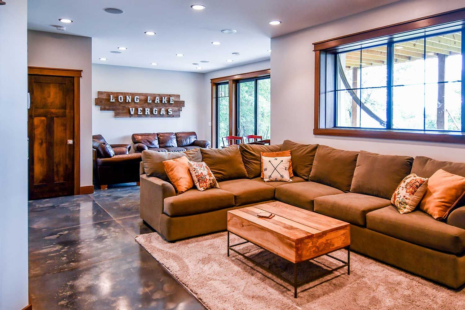 Lounge area with brown sectional sofa, wood coffee table, and large window.