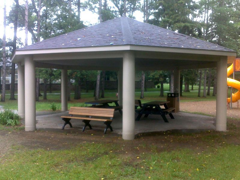 A pavilion with picnic tables and benches in a park setting.