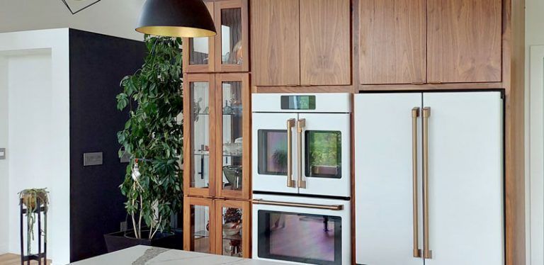 Kitchen with wood cabinetry, white appliances, and a large green plant.