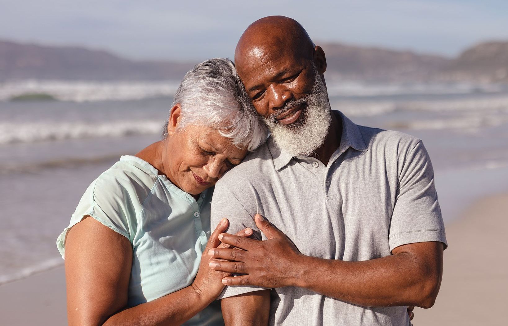 A man and a woman are hugging each other on the beach.