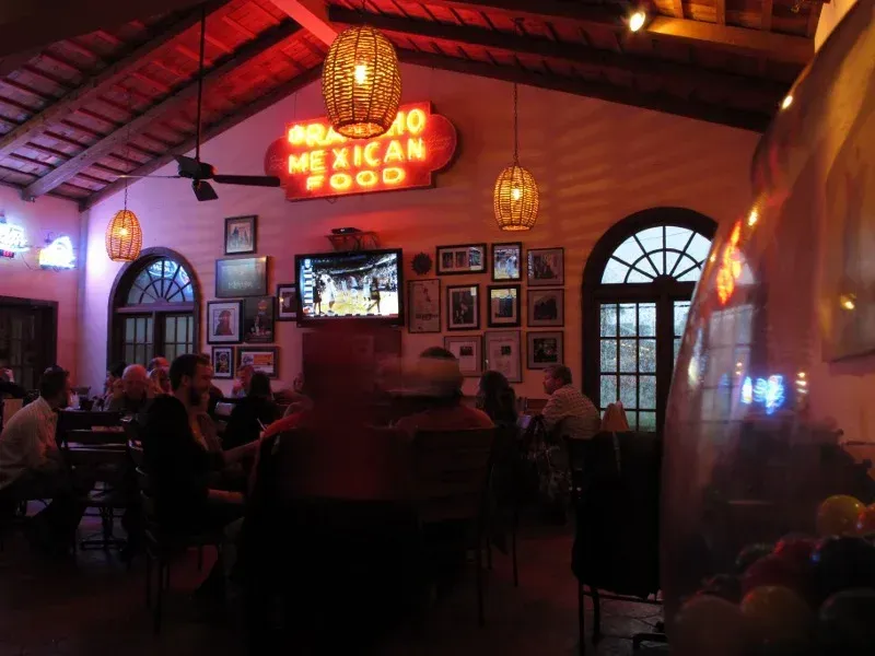A frosty margarita with a salted rim catches the glow of the neon inside Matt’s El Rancho, surrounded by sizzling fajitas, stacked enchiladas, and endless chips and salsa on a dark wooden table.