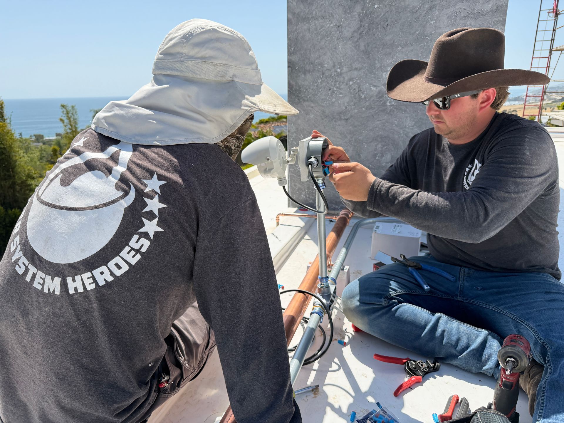 Two people on a boat deck adjusting a camera mounted on a tripod near the water.