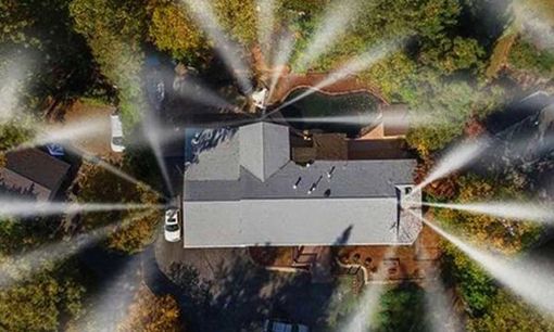 Technician in blue coveralls checks a clipboard beside industrial control panels and tanks in a factory.