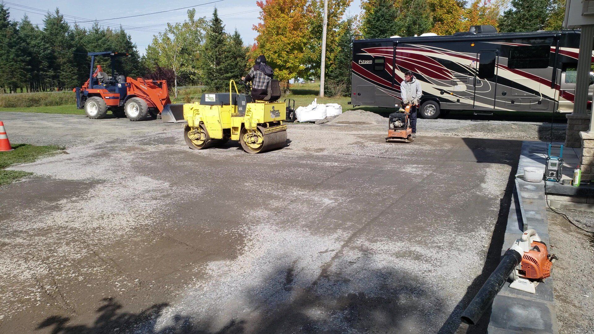 Un rouleau jaune est assis sur un parking à côté d'un camping-car.