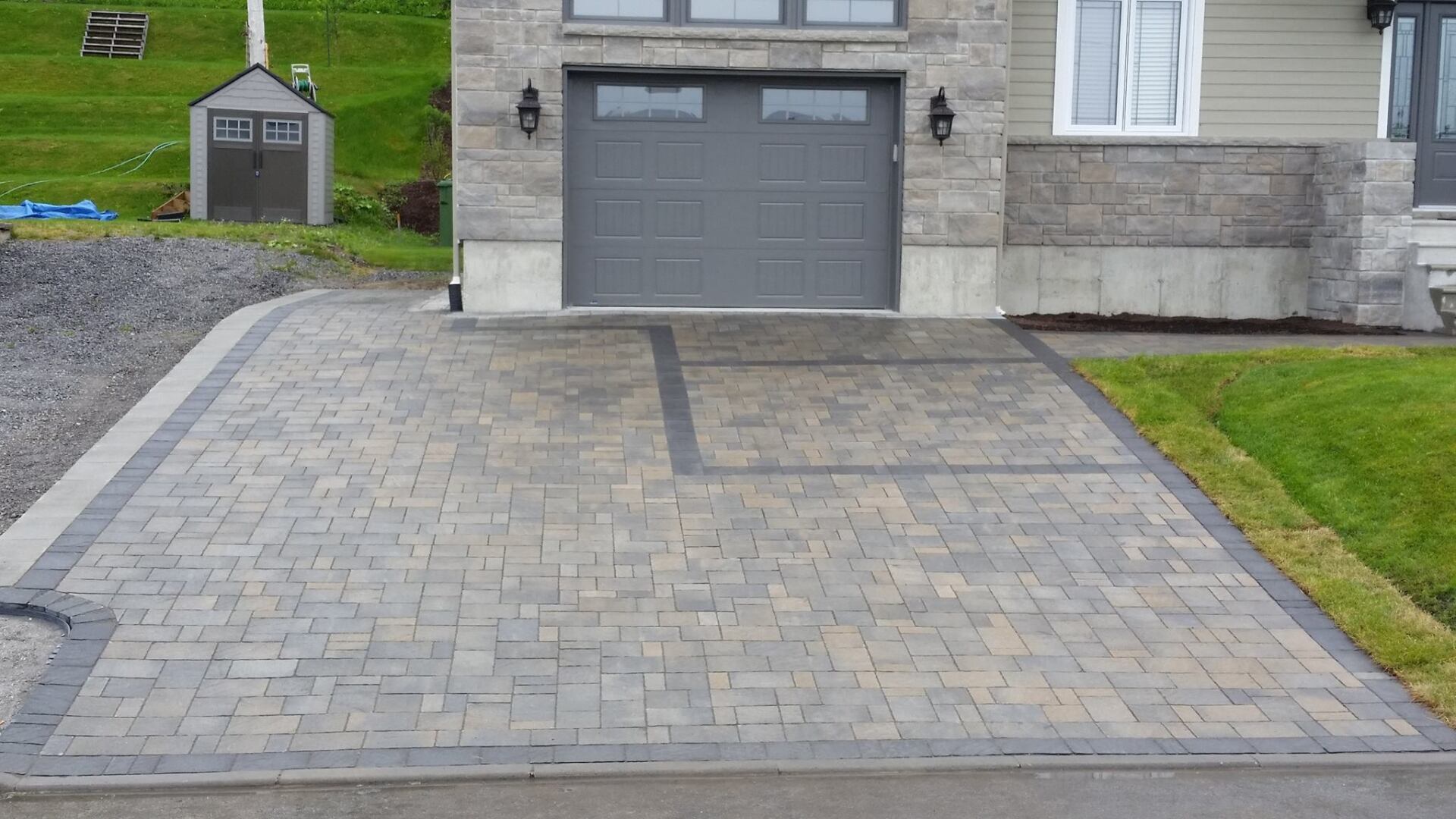 Une allée en briques menant à une porte de garage d'une maison.