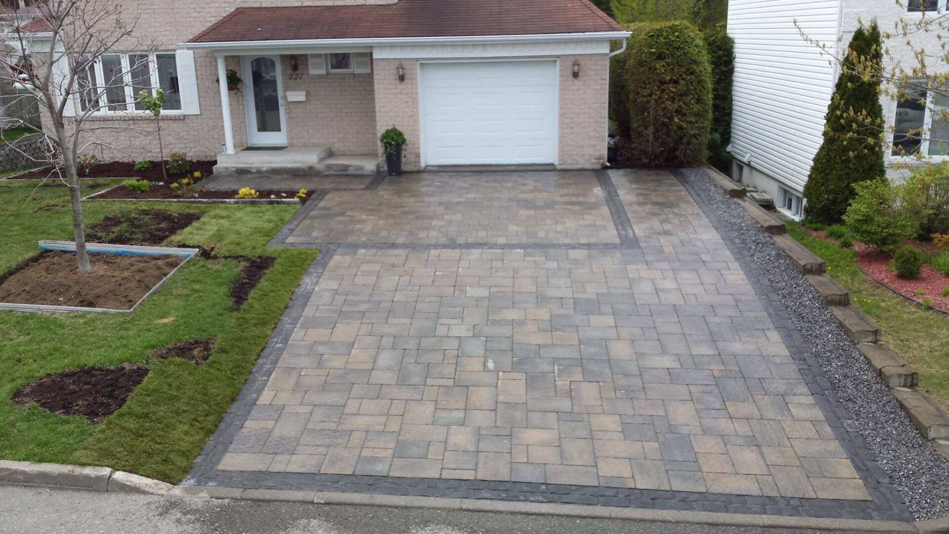 Une allée devant une maison avec une porte de garage blanche.