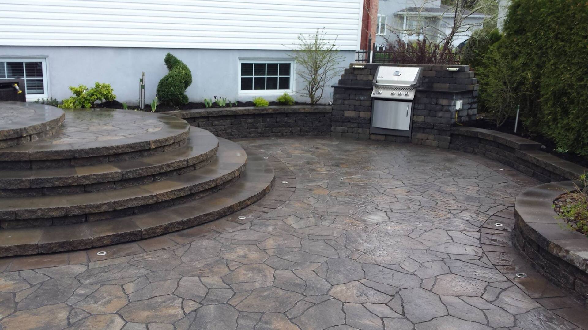 Un patio avec des escaliers et un grill devant une maison.