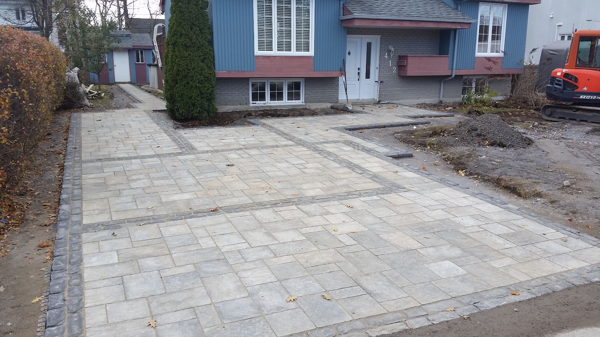 Une maison bleue avec une allée en briques devant elle