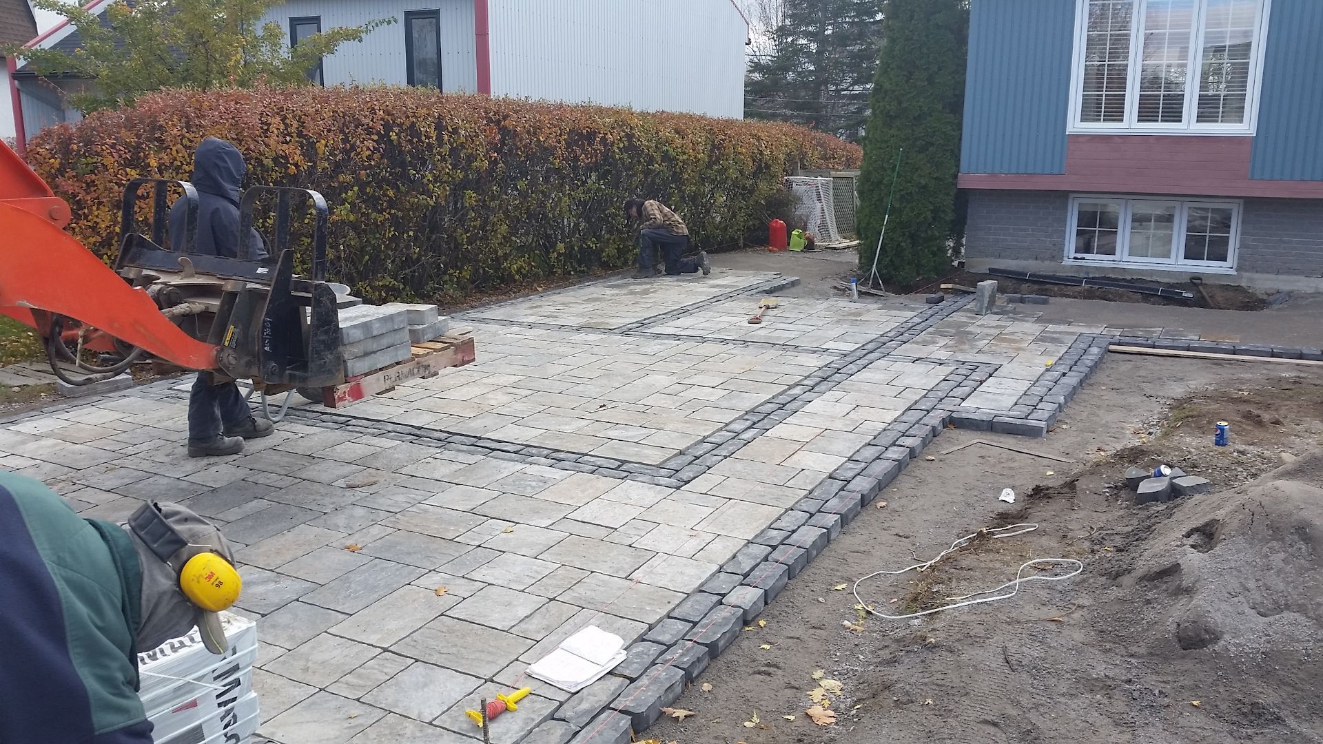 Un groupe de personnes travaille sur une allée devant une maison.