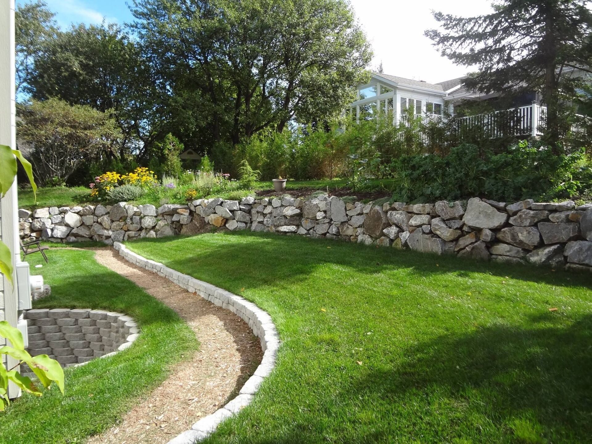 Une pelouse verte luxuriante avec un mur de pierre en arrière-plan