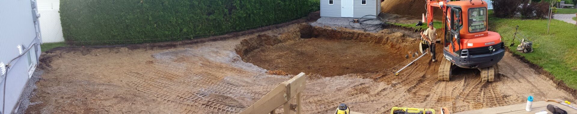 Un bulldozer creuse un trou dans la terre devant une maison.