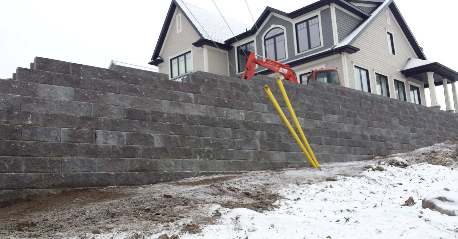 Une grande maison est en construction à côté d'un grand mur de briques.