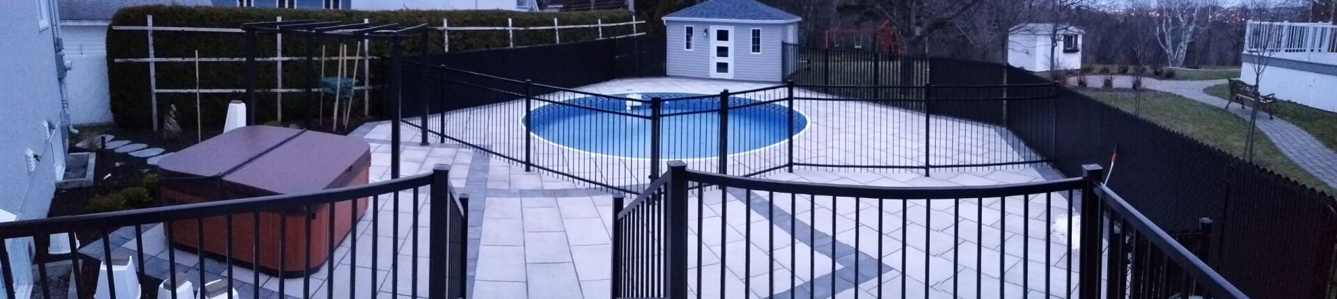 Une clôture entoure une piscine avec un gazebo en arrière-plan.