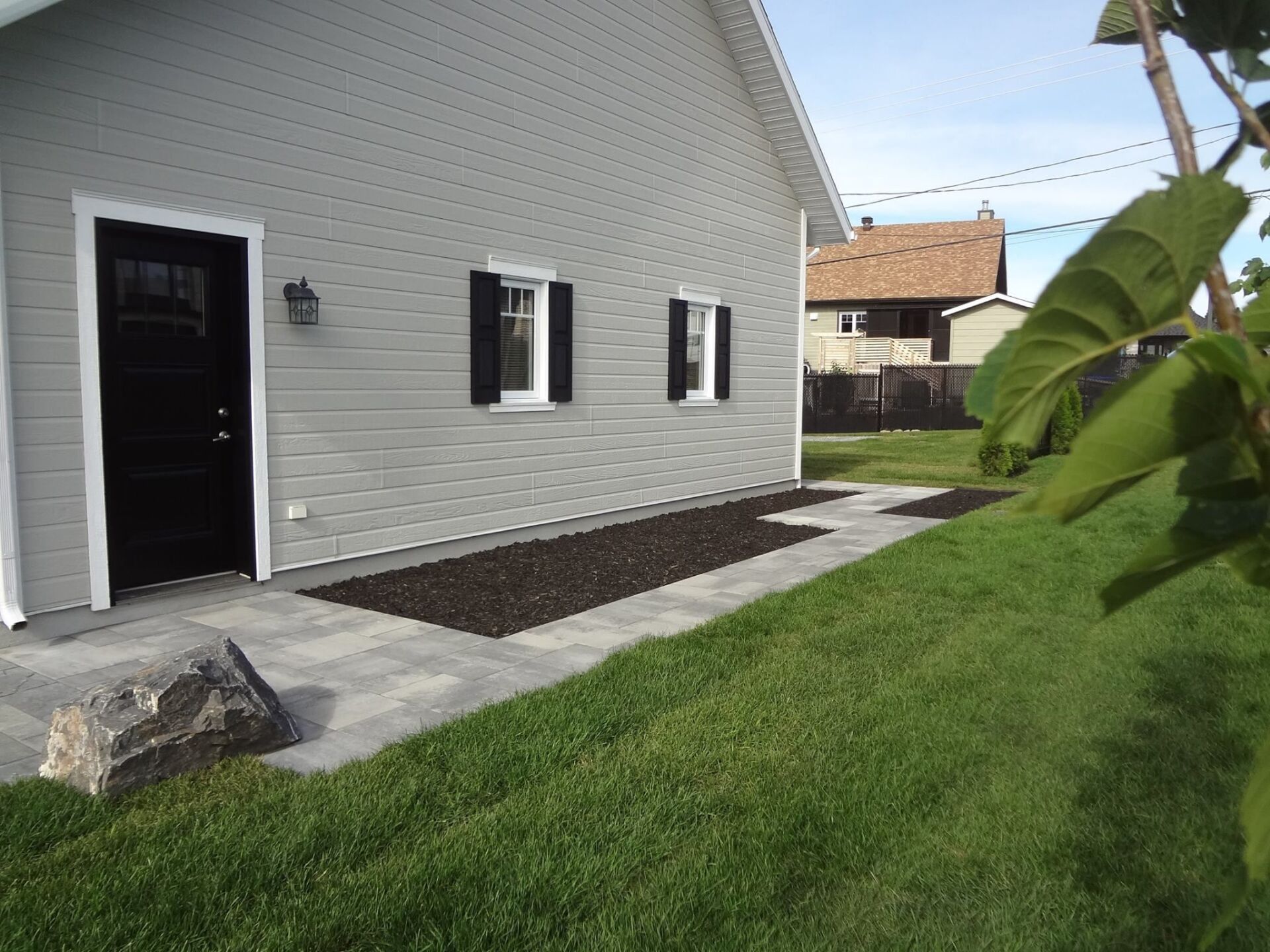 Une maison blanche avec des volets noirs et une passerelle qui y mène.