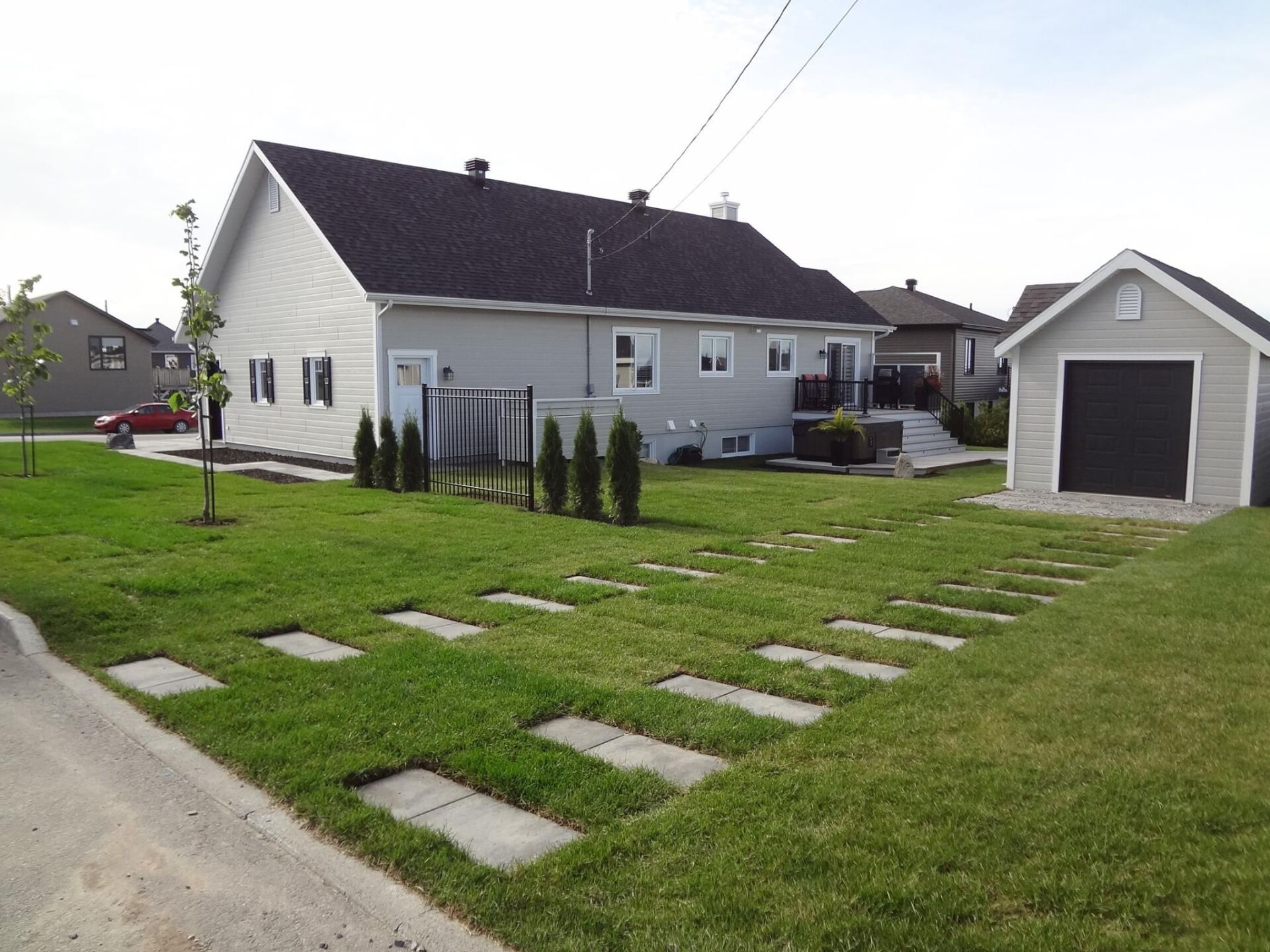 Une maison blanche avec un garage noir à côté