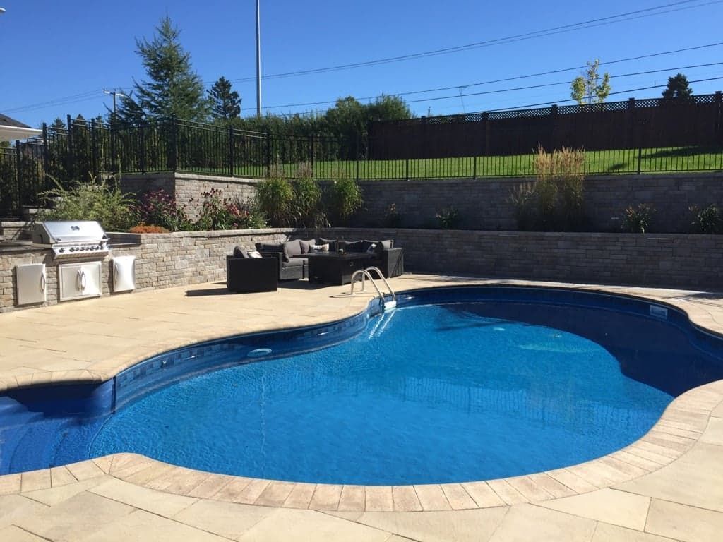 Une grande piscine avec un barbecue dans l'arrière-cour