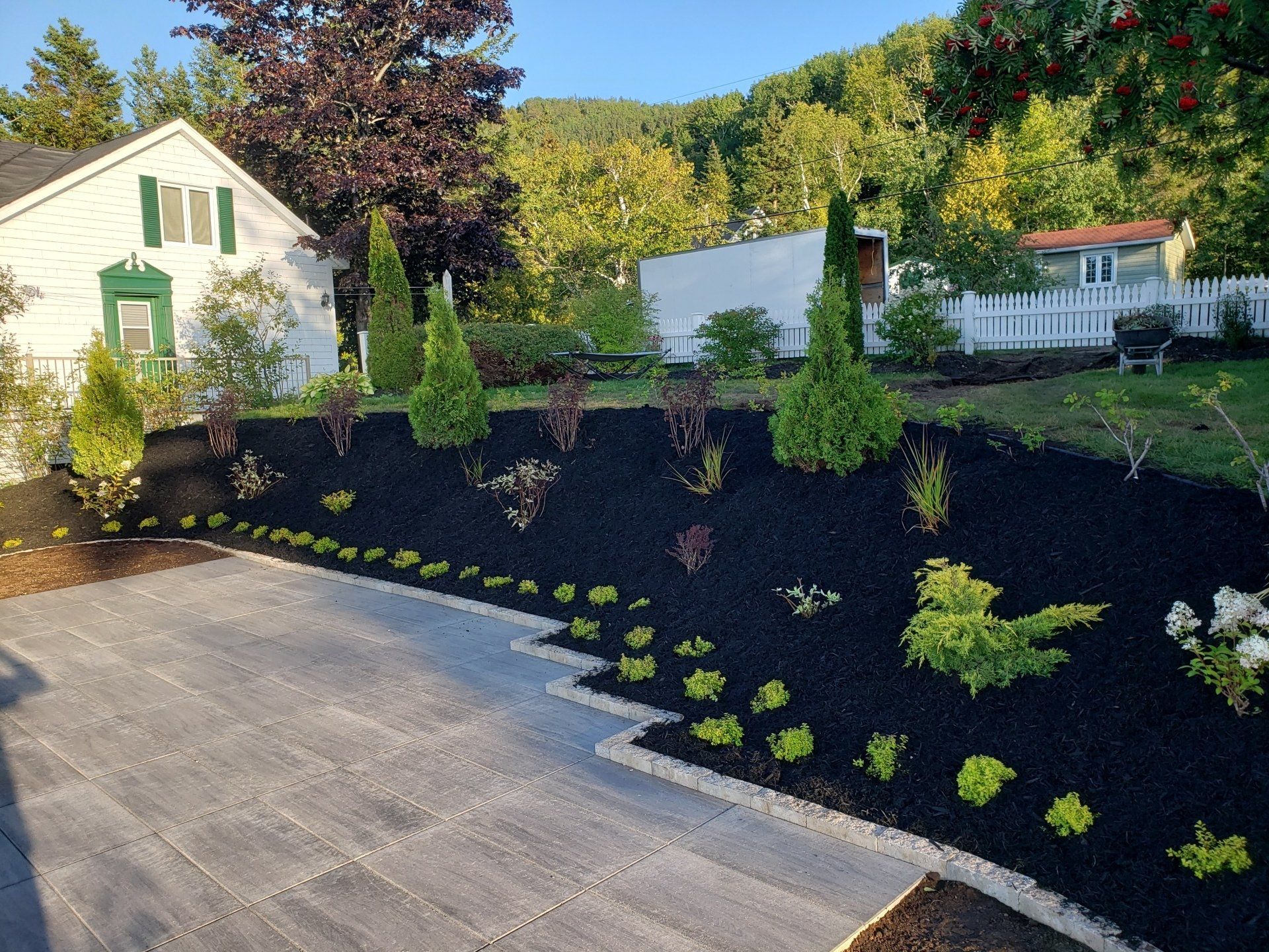 Une maison blanche avec une clôture blanche est entourée d'une cour verdoyante.