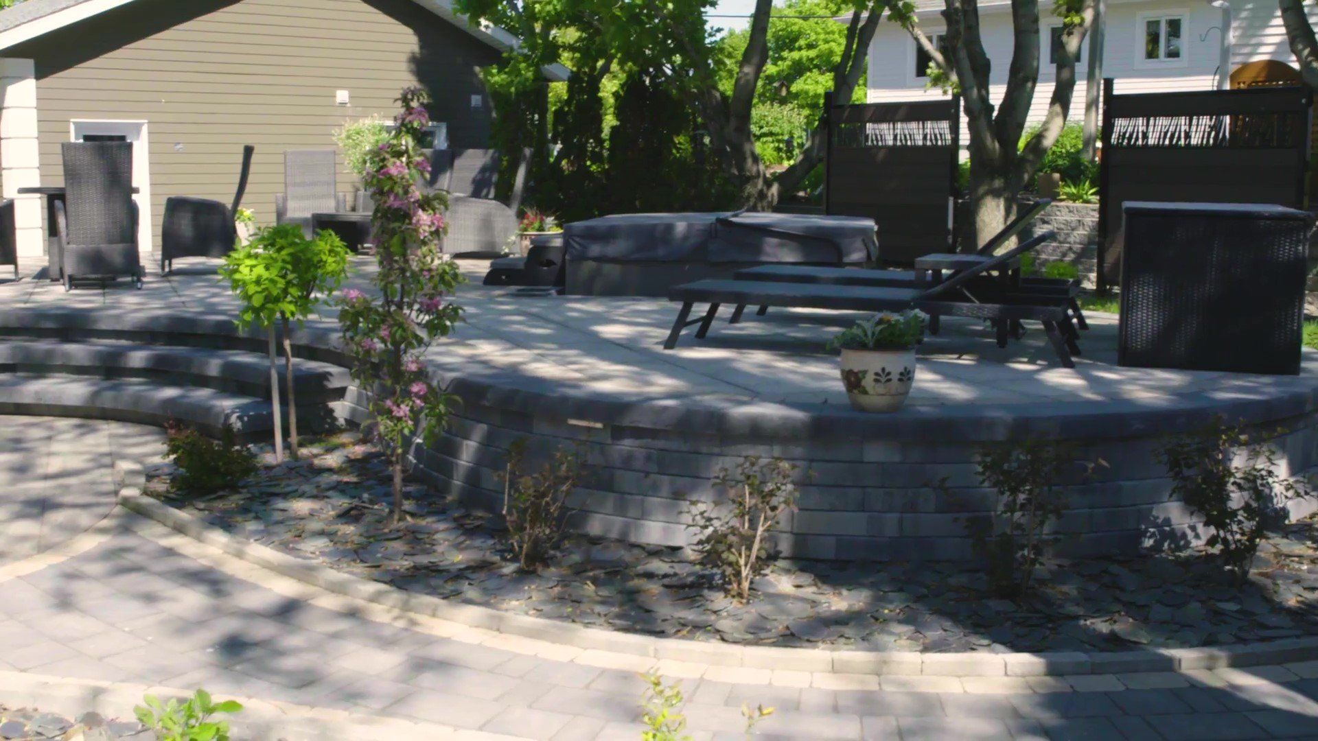 Un patio avec un canapé, des chaises et une plante en pot devant une maison.