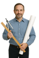 Man with drafting tools, blueprints; wearing blue shirt, smiling against white backdrop.