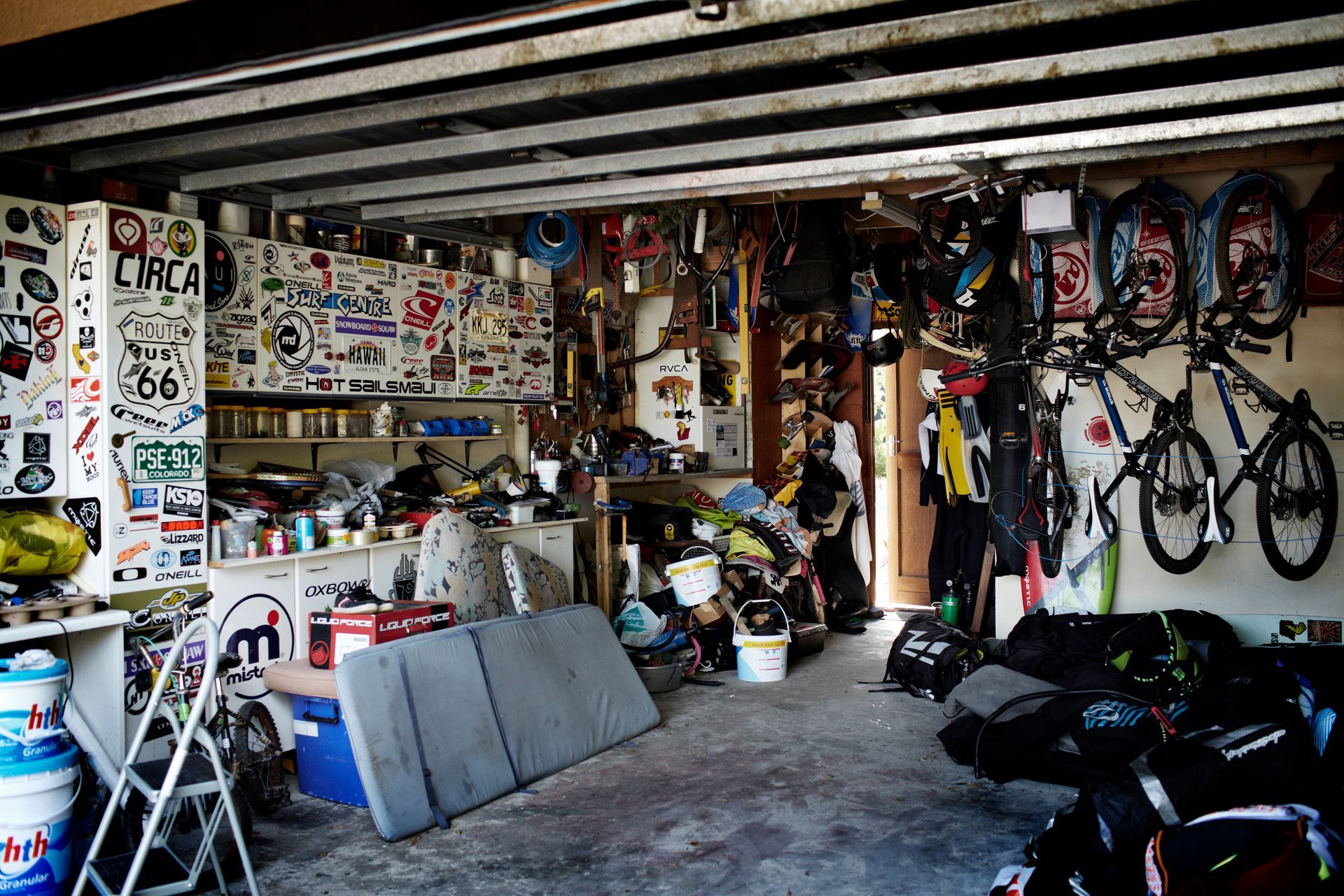 Cluttered garage with tools, gear, bikes, and stickers.