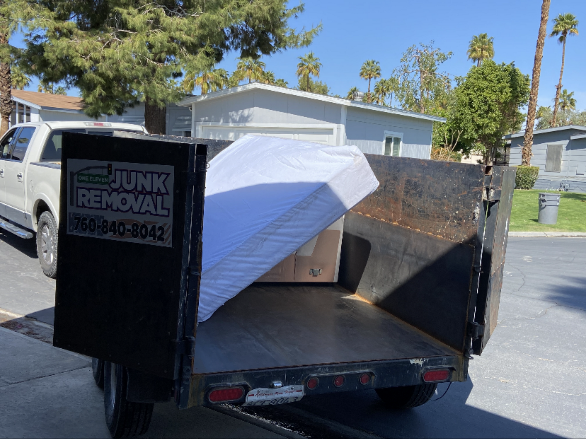 A mattress and other items loaded in a junk removal trailer in a residential neighborhood. A mattress and other items loaded in a junk removal trailer in a residential neighborhood.