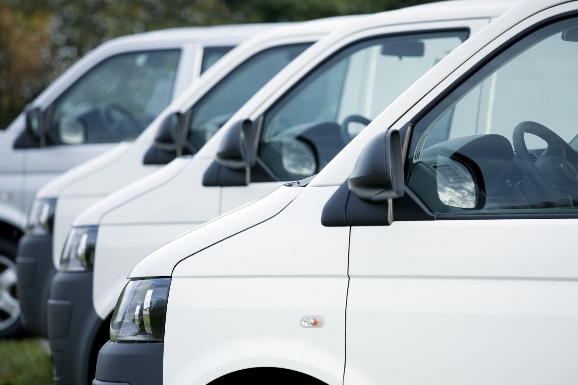 A row of white vans are parked next to each other.