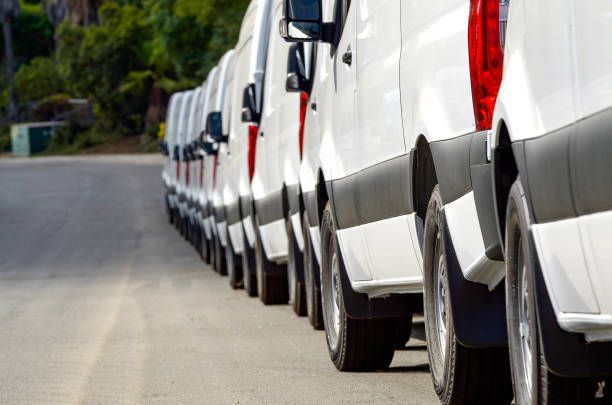 A row of white vans parked on the side of the road.