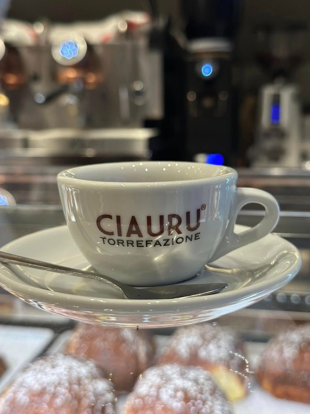 Piatto di frutti di mare con limoni e arance su un tavolo; bottiglie e bicchiere di vino sullo sfondo.