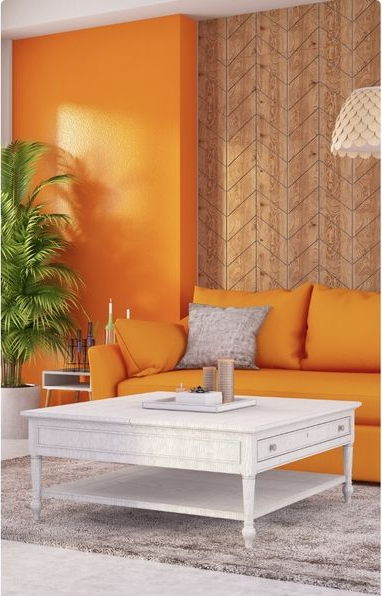 Orange-walled living room with orange couch, white coffee table, and textured wood wall.