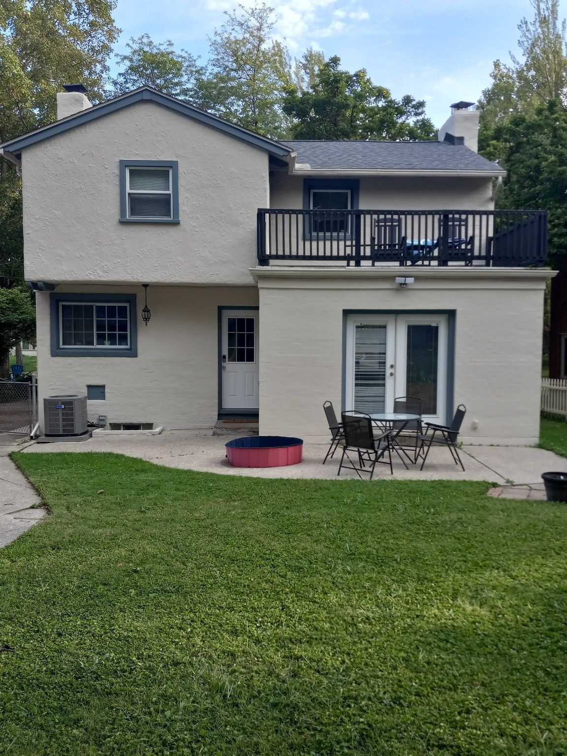 Backyard view of a two-story house with a patio, grass, and outdoor furniture.