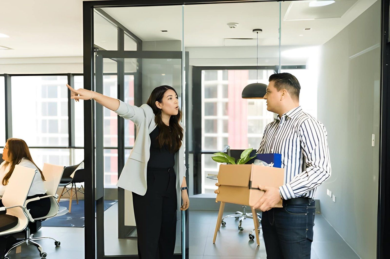 A Person Gestures Toward a Doorway While Another Holds a Box — Australian Employee Lawyers in Broadbeach Waters, QLD