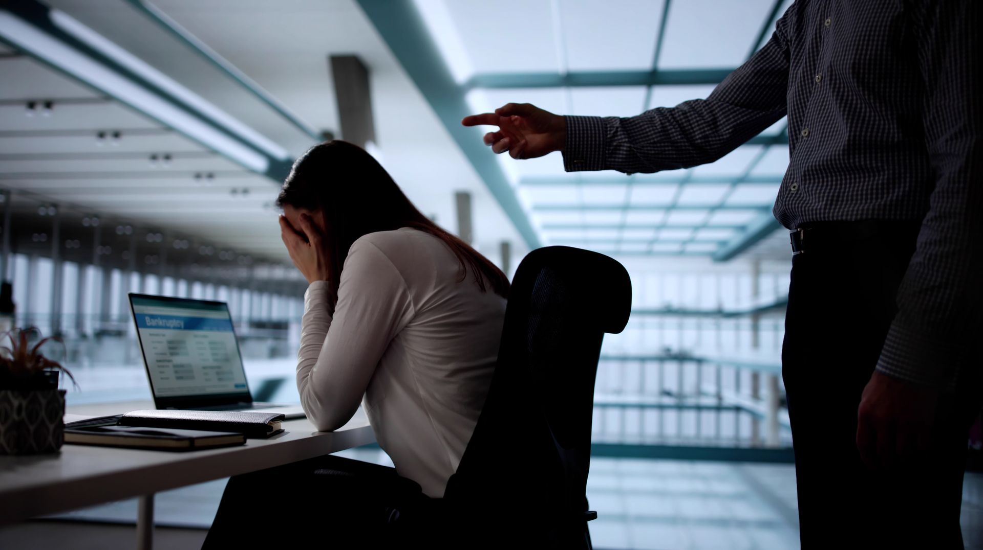 A Person Sits at a Desk While Another Person Points at Them — Australian Employee Lawyers in Broadbeach Waters, QLD