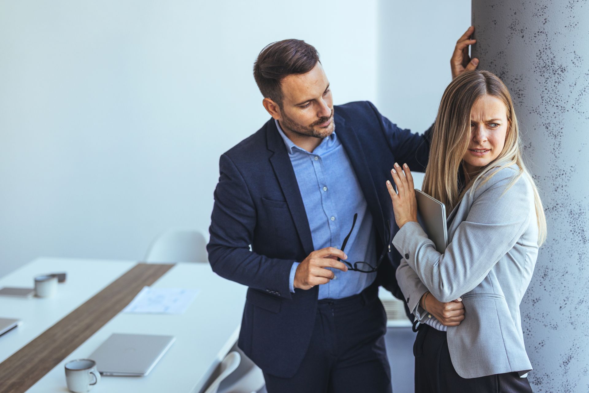 A Man in a Suit Leans Toward a Woman Standing by a Pillar — Australian Employee Lawyers in Broadbeach Waters, QLD