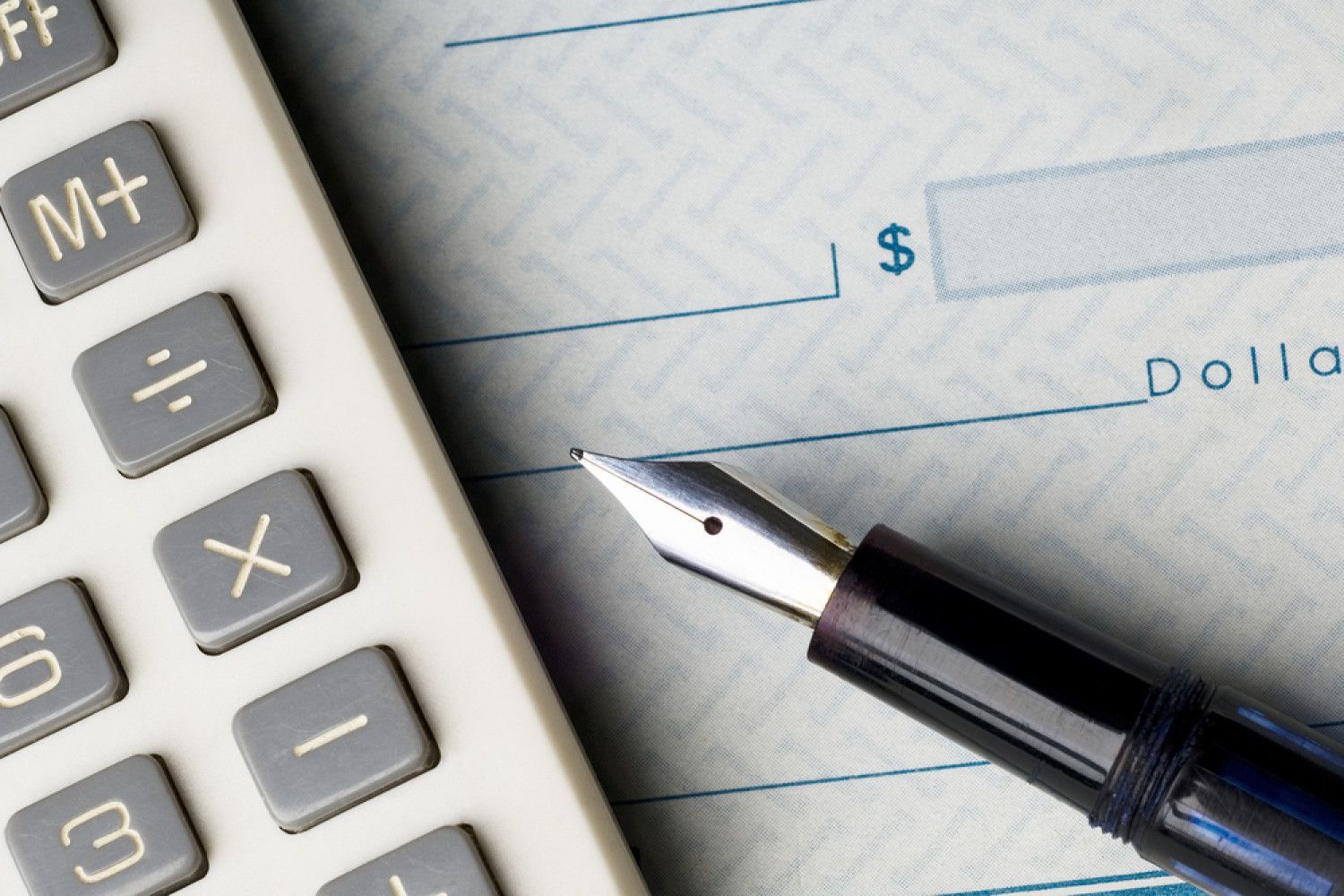 A fountain pen is sitting on top of a check next to a calculator