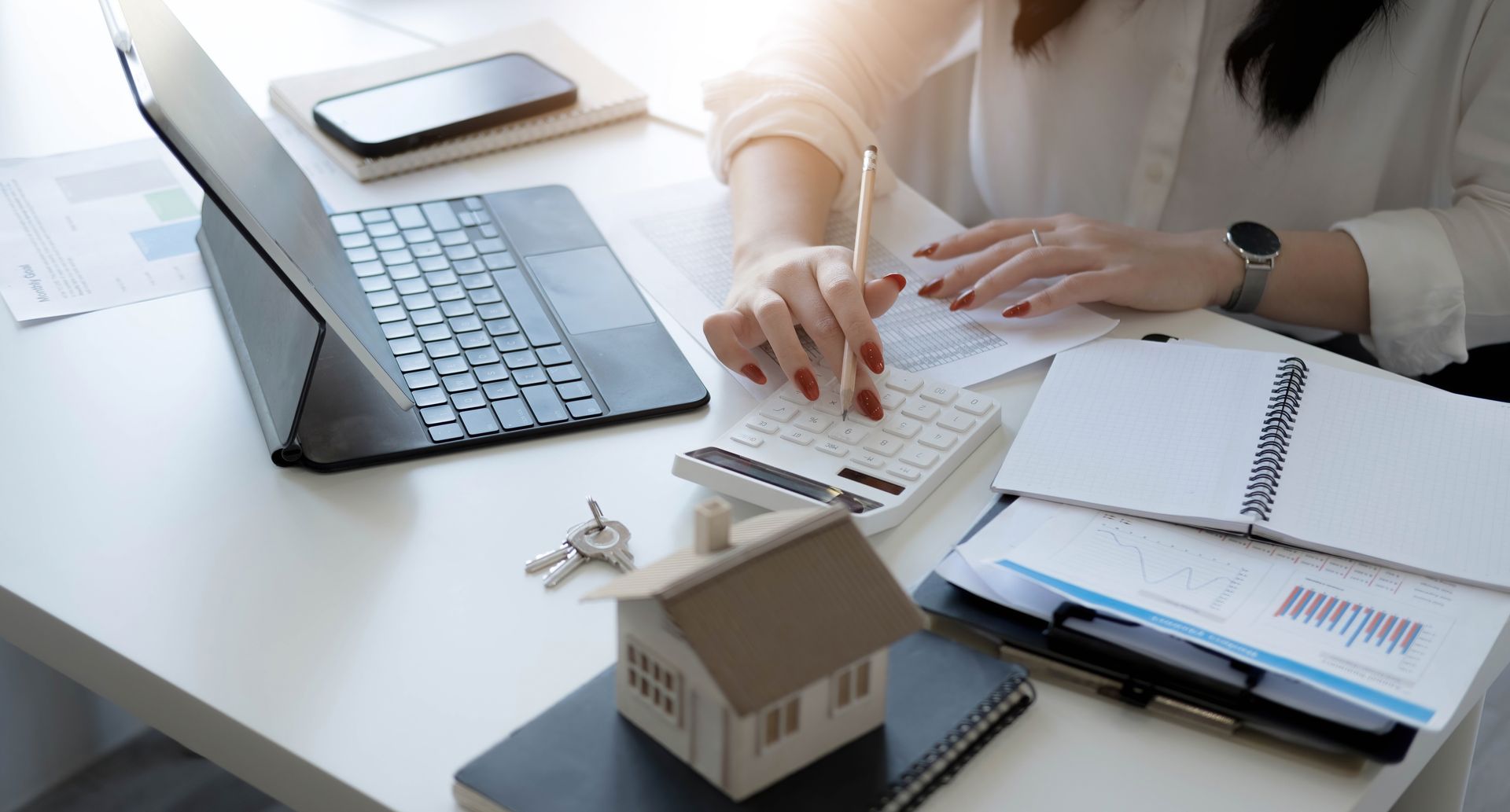 A woman is sitting at a desk using a laptop and a calculator.