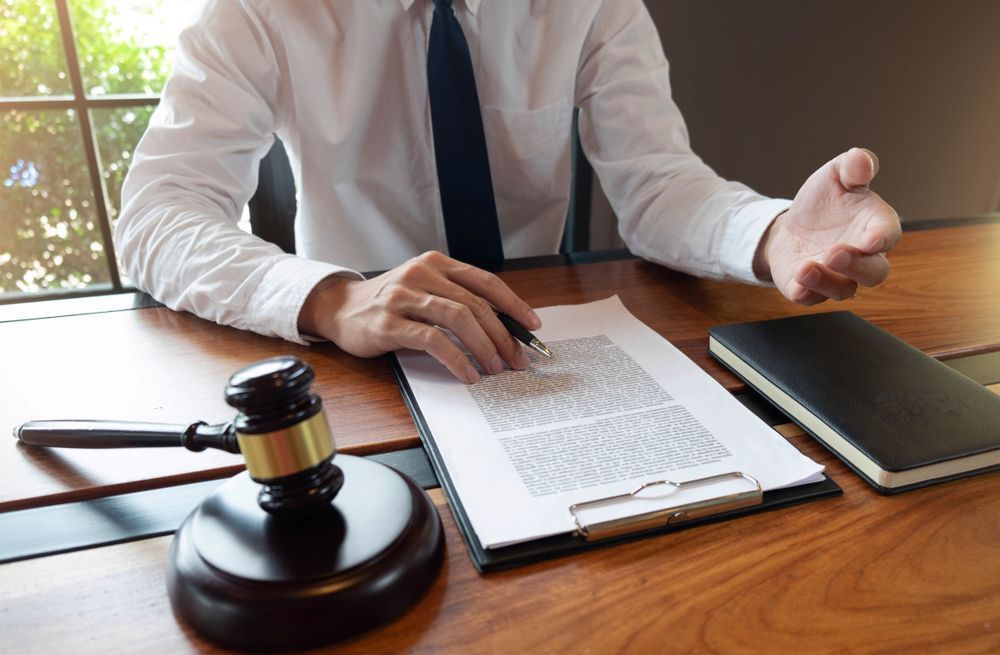 A man is sitting at a desk with a clipboard and a judge 's gavel.