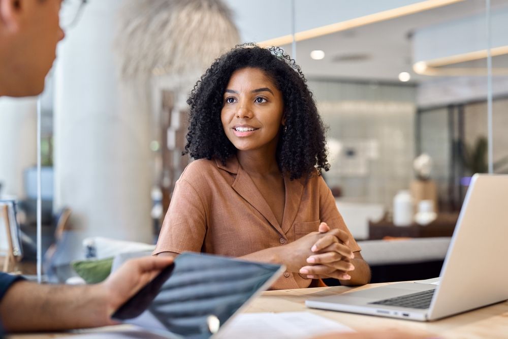 A woman is sitting at a table with a laptop and a tablet.